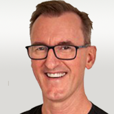 image is of Andy Brown. He is smiling with square glasses.